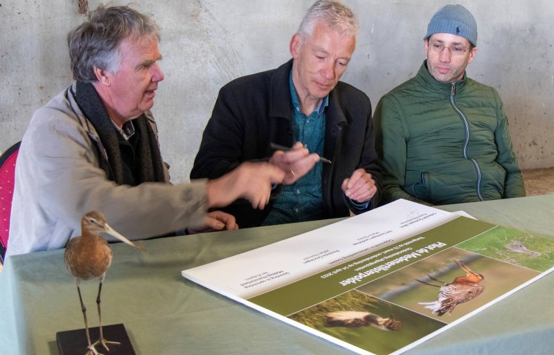 Voorzitter Freek Nieuwenhuis van het Collectief Groningen West, directeur Marco Glastra en boerenvertegenwoordiger Jan Kuipers tekenen de verklaring voor een weidevogelpilot in de Medenertilsterpolder.