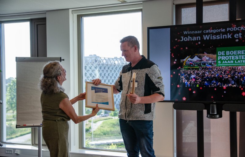 Videoredacteur en podcastmaker Johan Wissink van Nieuwe Oogst onvangt de Gouden Greep uit handen van jurylid Jacqueline Wijbenga.