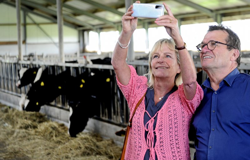Raadsleden maken foto's op de melkveehouderij.
