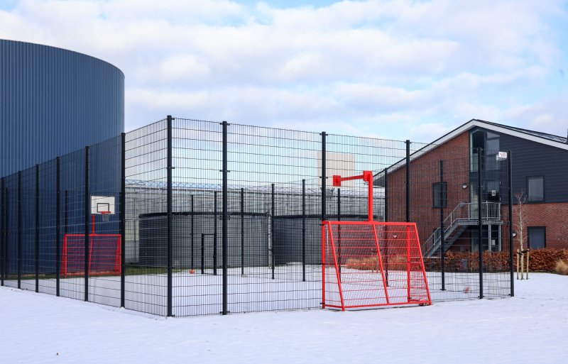 Achter de nieuwe woonunits op het erf is een sportkooi geplaatst.